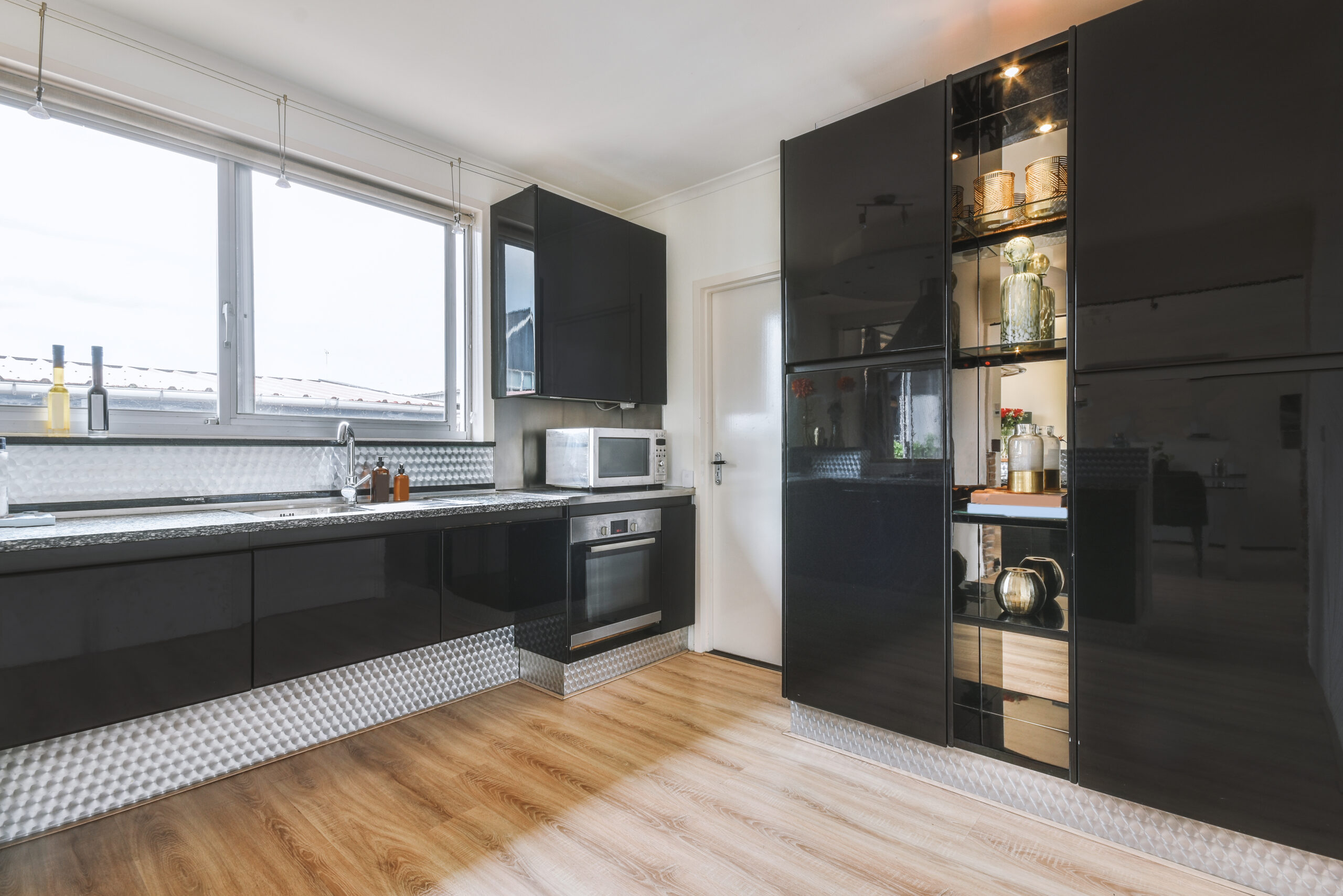 Contemporary minimalist style interior design of light studio apartment with wooden table and chairs in dining zone between open kitchen and living room with white walls and parquet floor